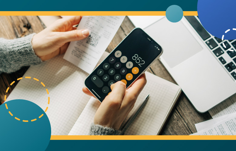 Close-up of person looking at a calculator on a phone surrounded by receipts, laptop and notebook