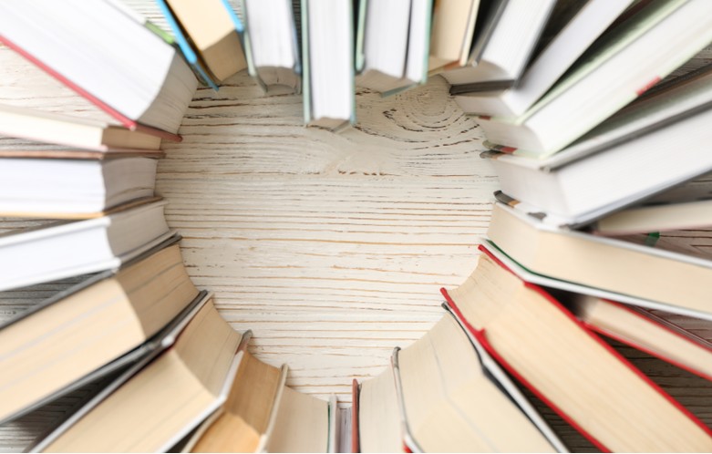 Books stacked on a wooden table in the shape of a heart.
