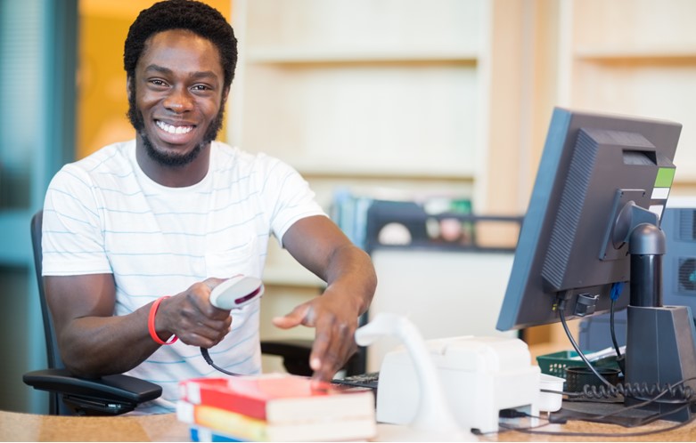 Male librarian scanning books