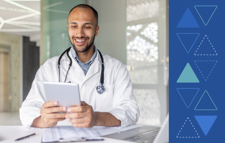 Smiling health care professional in a white coat using a tablet at a desk