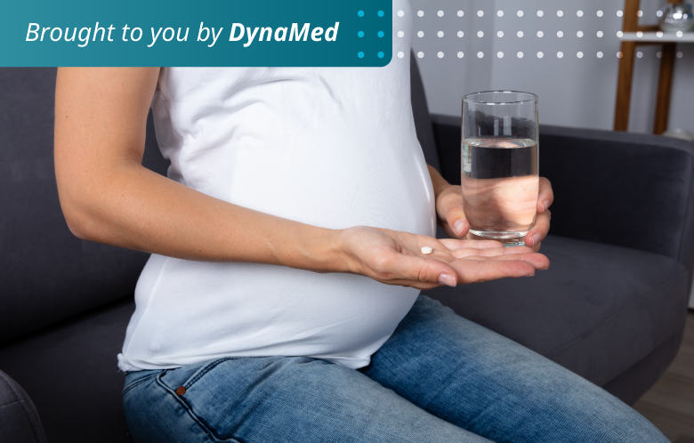 Pregnant woman holding glass of water and medicine