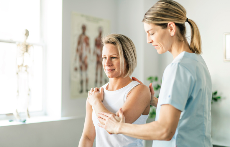 Female therapist helping patient with shoulder