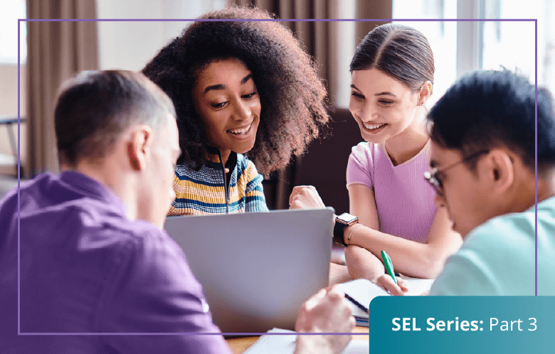 Group of four high school students working together :writing & looking at a laptop