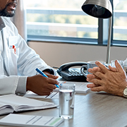 Close up of doctor and patient talking at desk, doctor has a pen in his hand