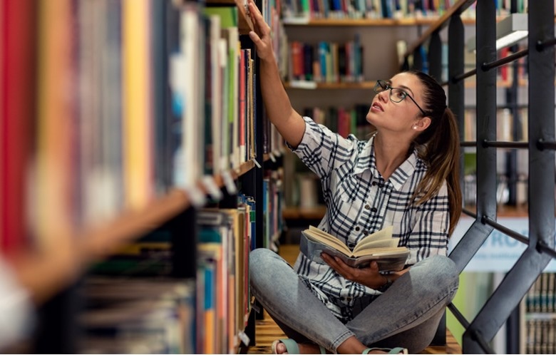 a student reaching for a book in a library