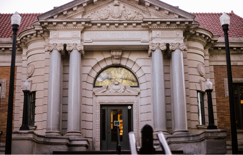 Exterior of the Kendall Young Library, a stone facade with columns, a staircase, and black double doors.