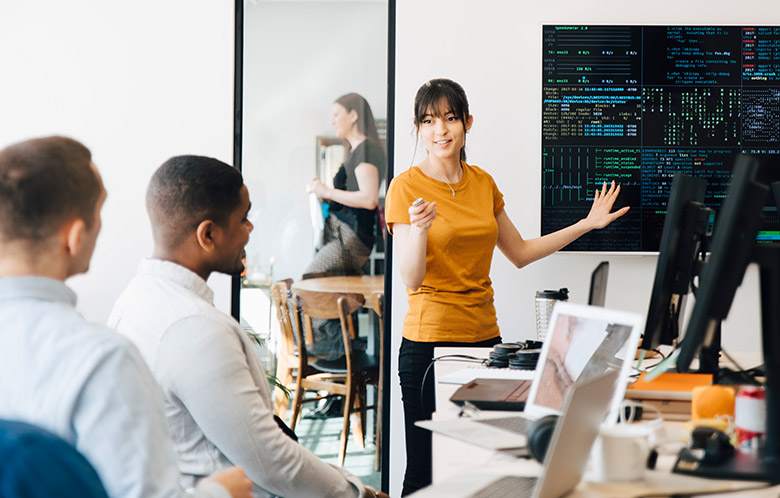 Female web engineer interacting with colleagues while giving presentation in office