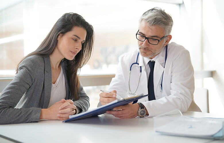 female patient discussing paperwork with male doctor at table