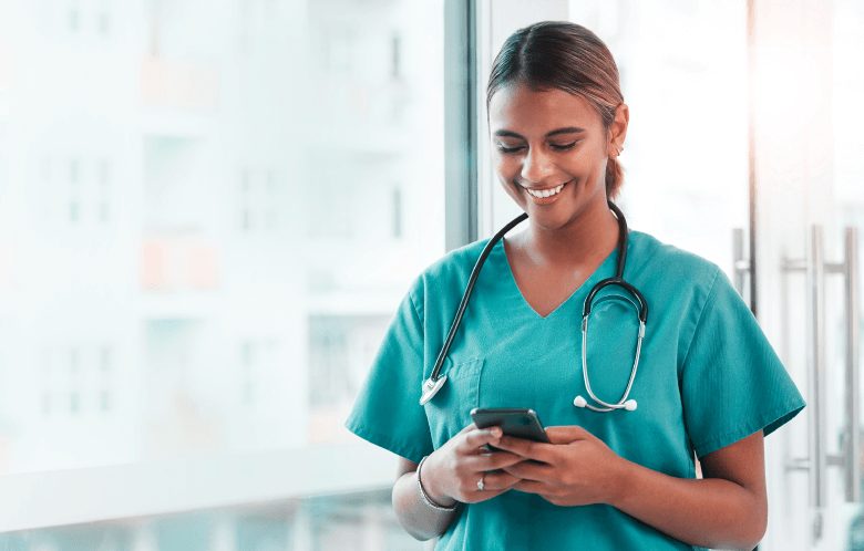 nurse working in hospital smiling looking at her phone