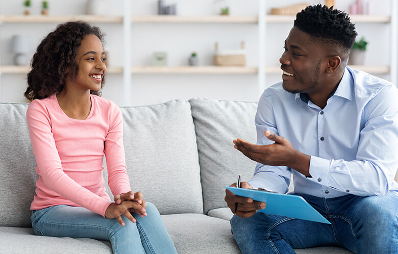 young female teenager talking to male therapist on couch
