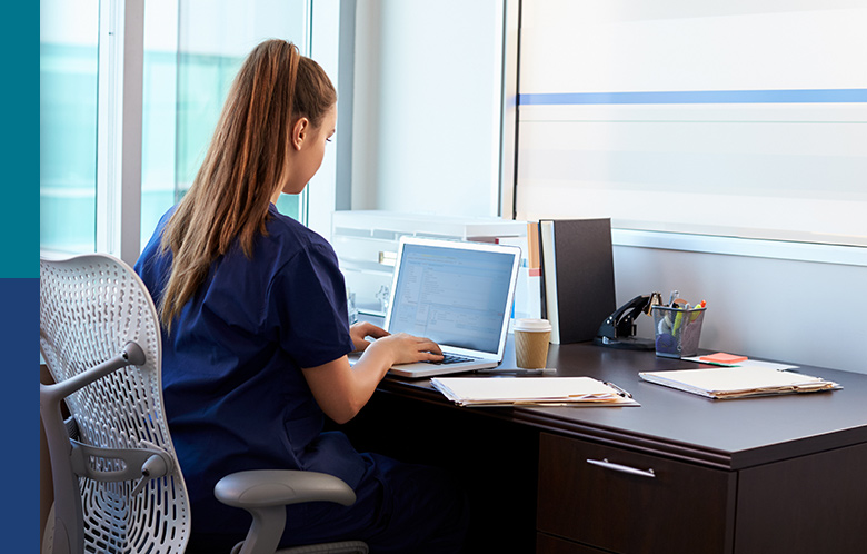 Nurse sitting at a desk typing on a laptop