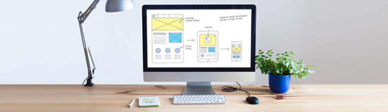 Desktop computer showing wireframe sketch of responsive web designs on multiple devices