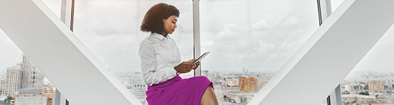 Black woman in skyscraper building on tablet