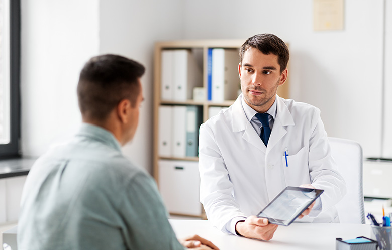 male doctor showing male patient tablet in doctor's office