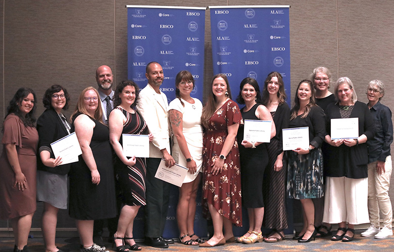 John Cotton Dana Awards winners posing in front of banner stands, holding certificates. 