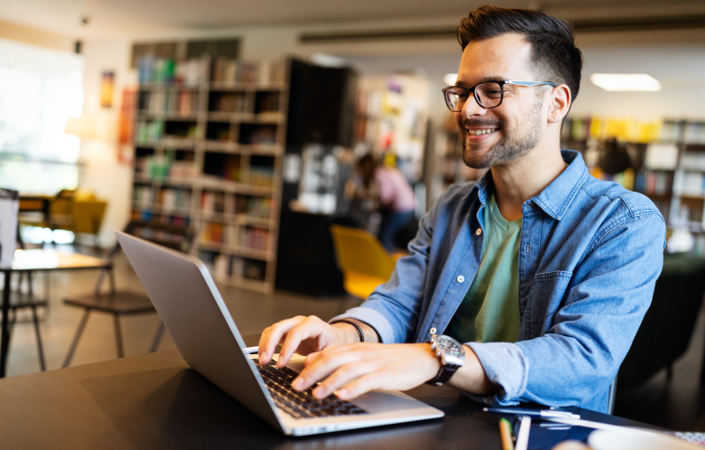 male researcher working on laptop in a library