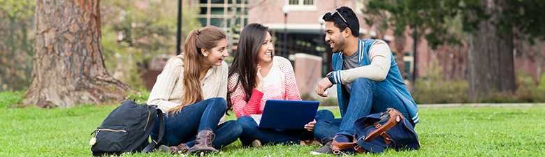 Students sitting on the grass outside on a college campus