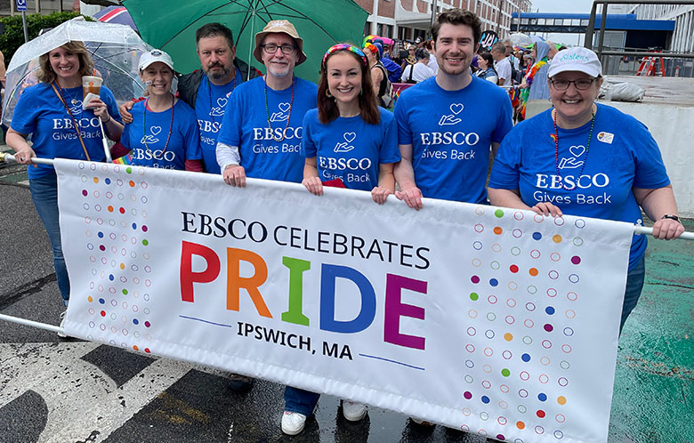 EBSCO workers walking in Pride parade with banner that says "EBSCO Celebrates Pride, Ipswich, MA"