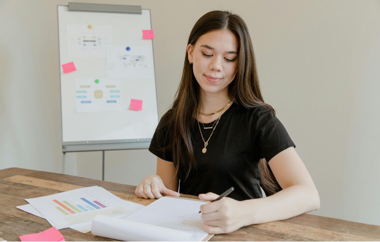 Young woman taking notes and looking at a chart