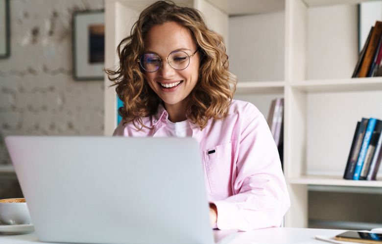 Smiling woman on a laptop in a library