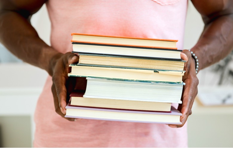 A woman holding a stack of books in her hands.