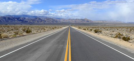Horizon of open road in the desert with mountains