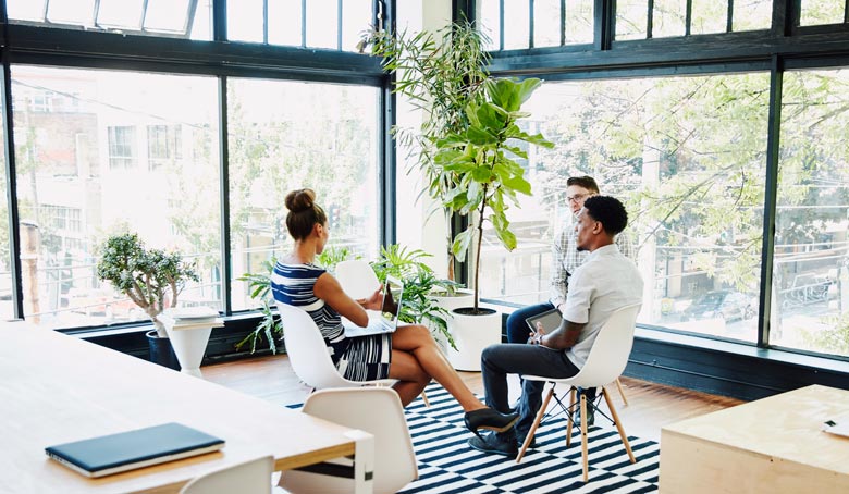 Three professionals meeting and collaborating in an office.