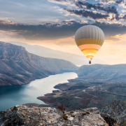 Hot air balloon in the sky over a river running through a canyon.