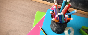 colorful notebooks, pens, pencils, tape on a desk